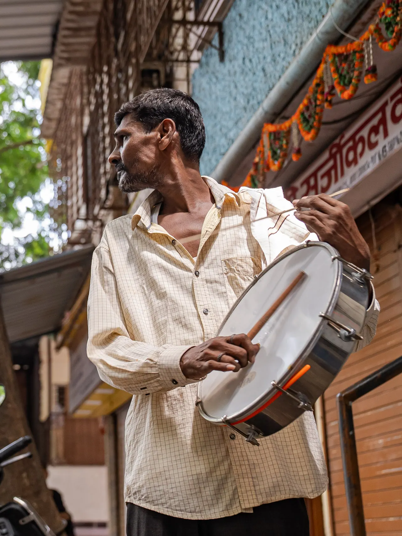 A performer plays the dhol in the street during a Nirmik procession.